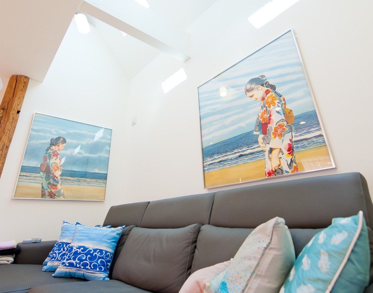 A living room with a couch and two paintings on the wall.