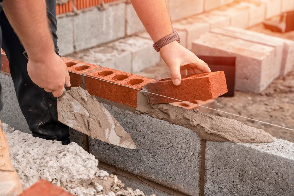 A man is laying bricks on a concrete wall.