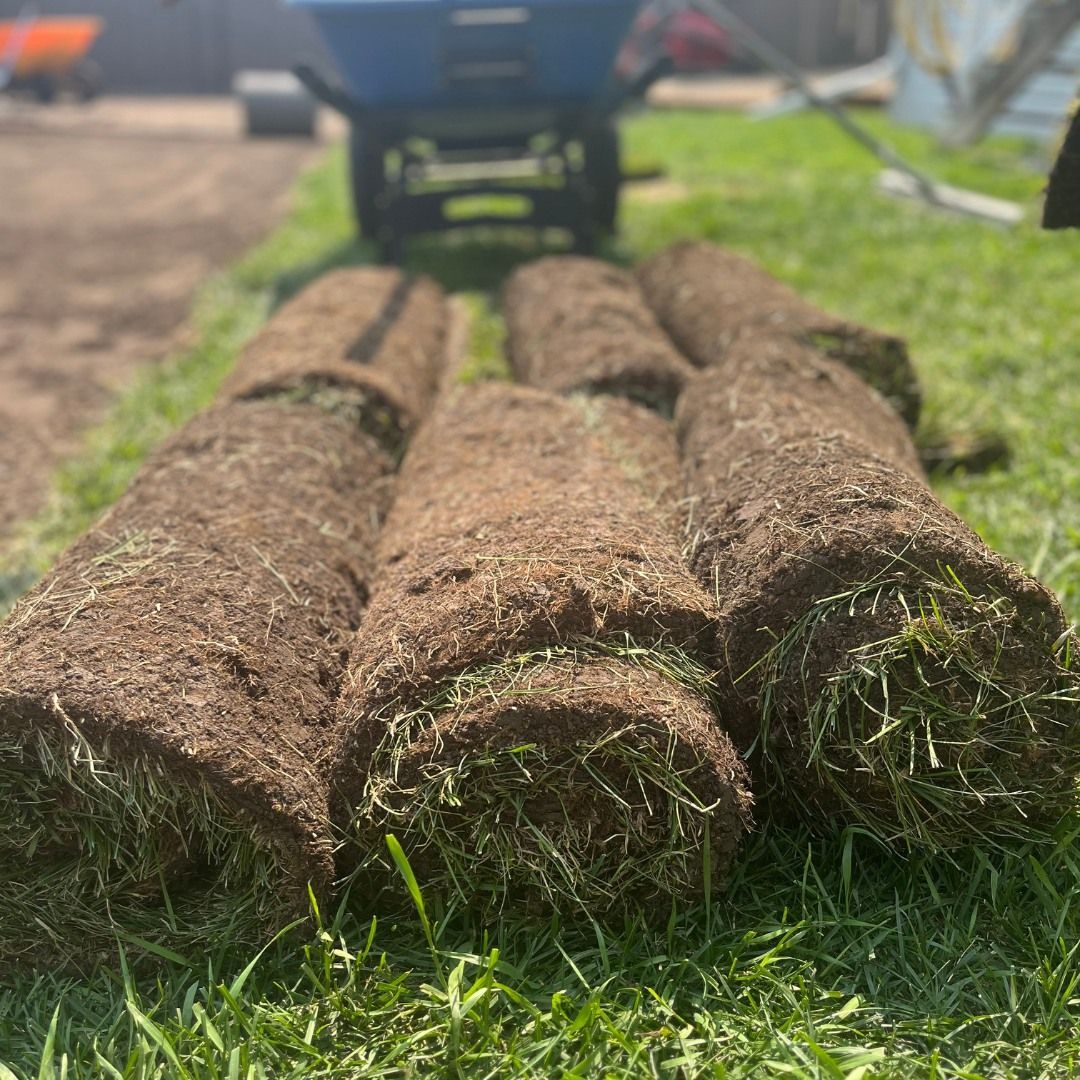 Three rolls of turf are sitting on top of each other on a lush green field.