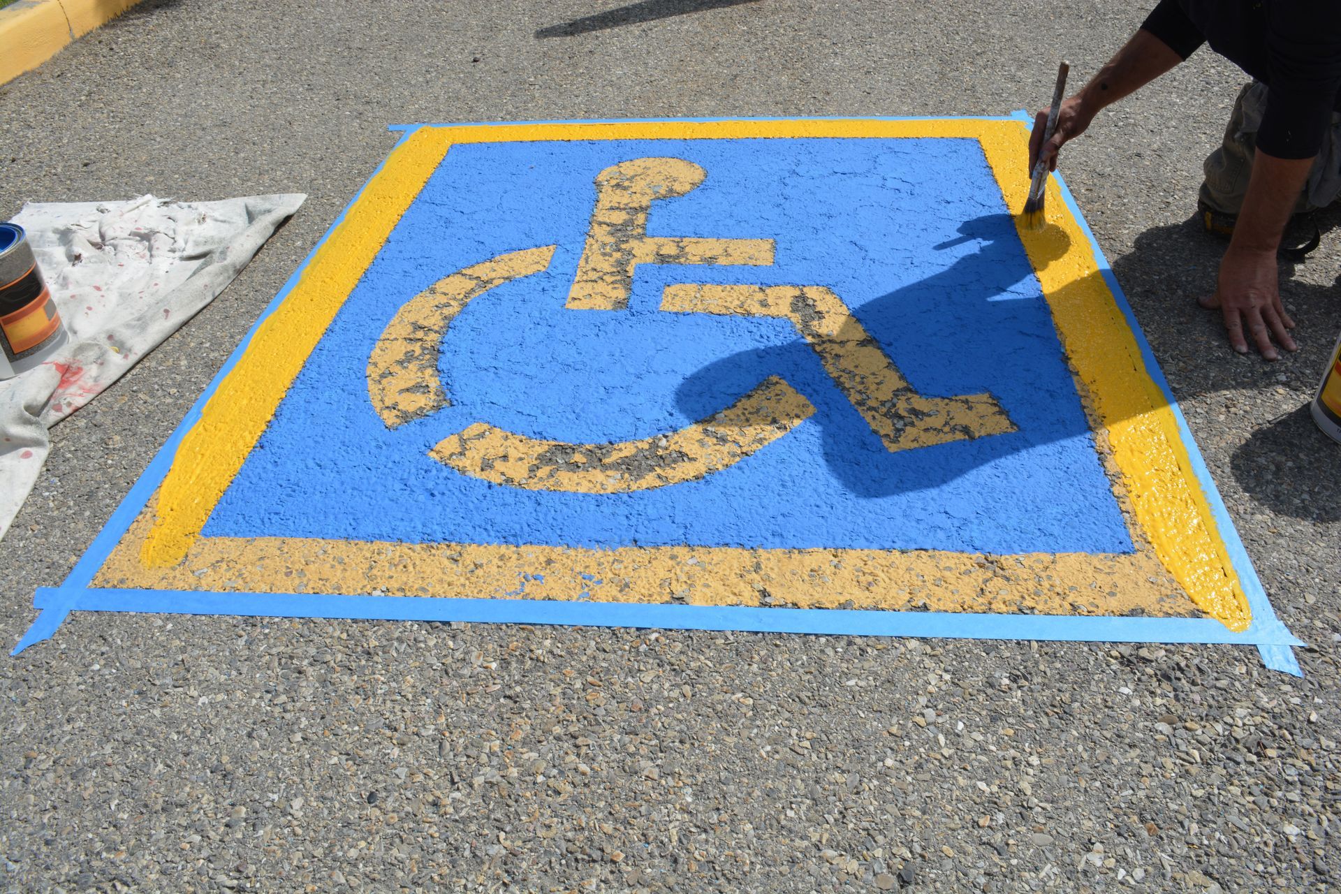 A person is painting a handicap sign on the ground