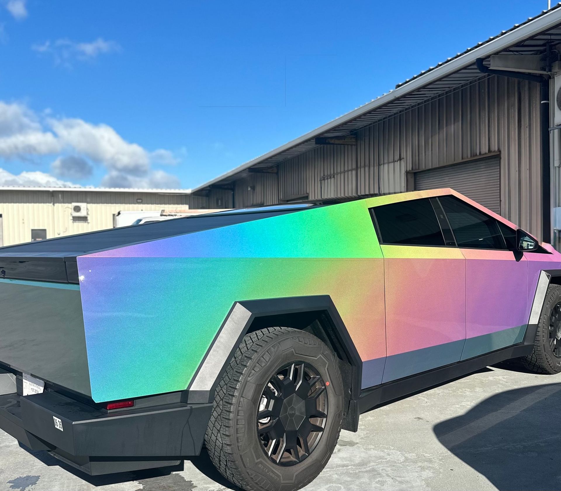A rainbow colored car is parked in front of a building