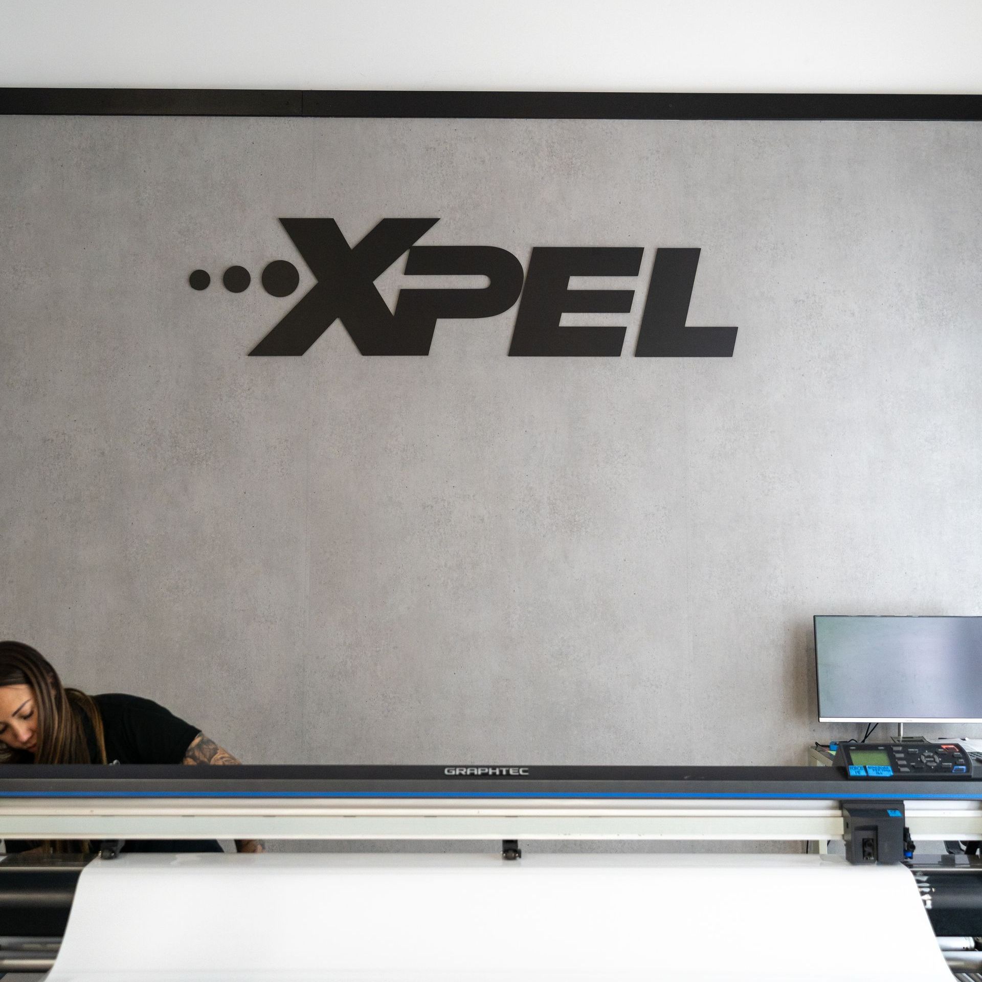 A woman sitting in front of a xpel machine