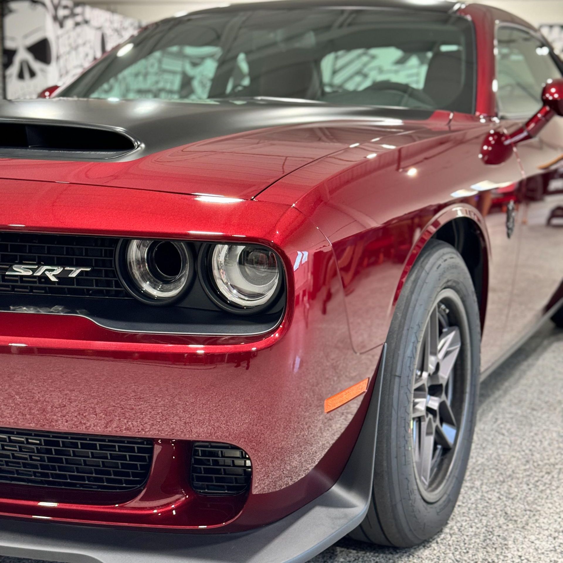 A red dodge challenger srt is parked in a garage