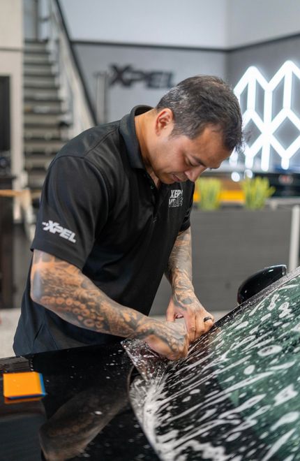 A person is applying protective film to the hood of a car.