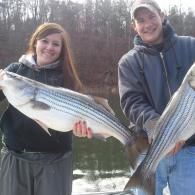 couple holding striped bass