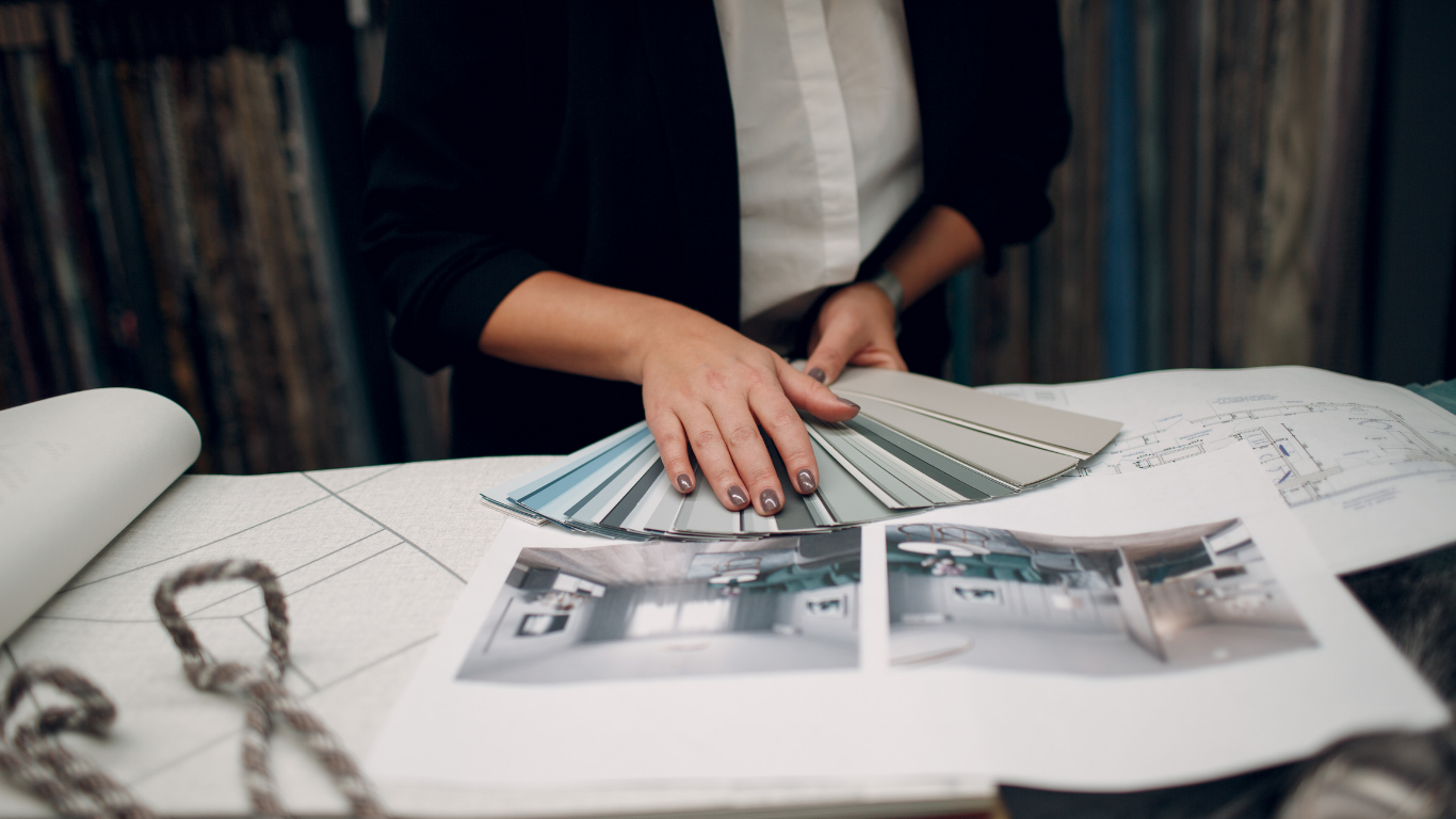 A woman is sitting at a table holding a fan of fabric samples.