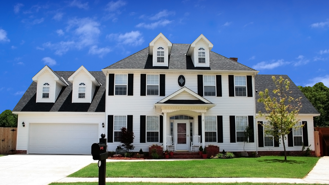 A large white house with black shutters and a mailbox in front of it