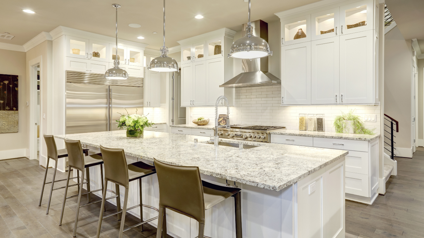 A kitchen with white cabinets , granite counter tops , stainless steel appliances and a large island.