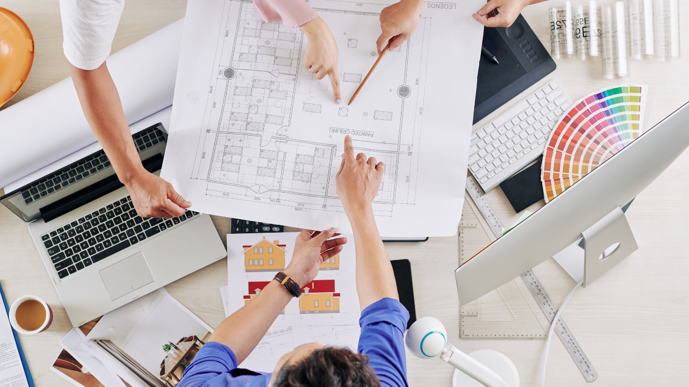 A group of people are sitting around a table looking at a blueprint.