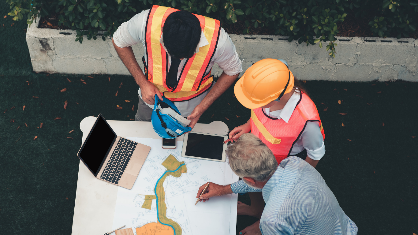 A group of construction workers are sitting at a table looking at a blueprint.