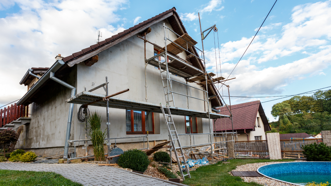 A house is being remodeled with scaffolding and a pool in the backyard.