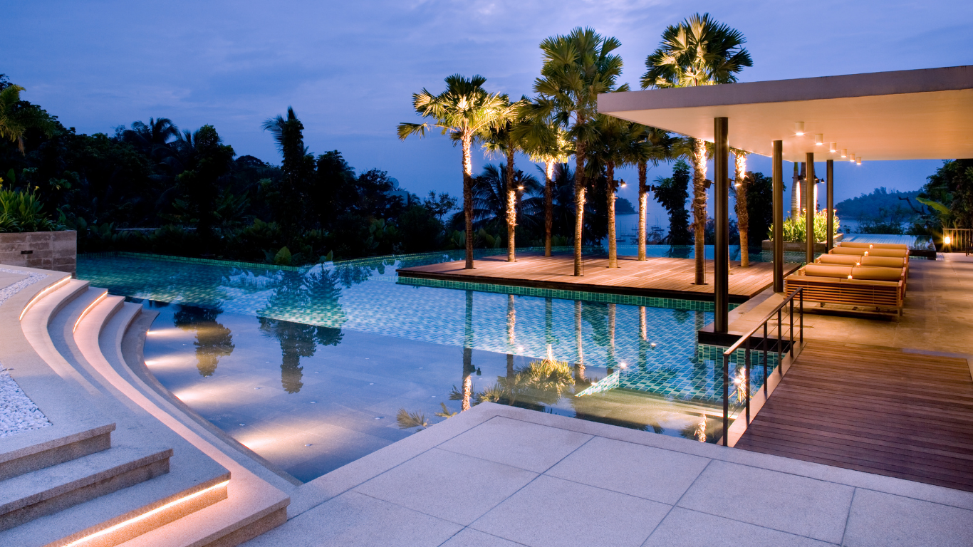 A large swimming pool surrounded by palm trees at night