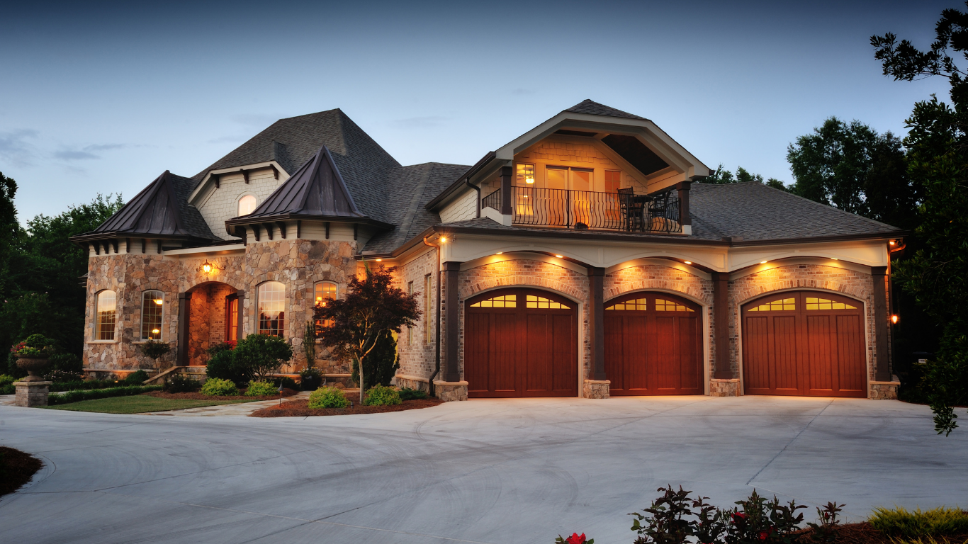 A large house with three garage doors is lit up at night