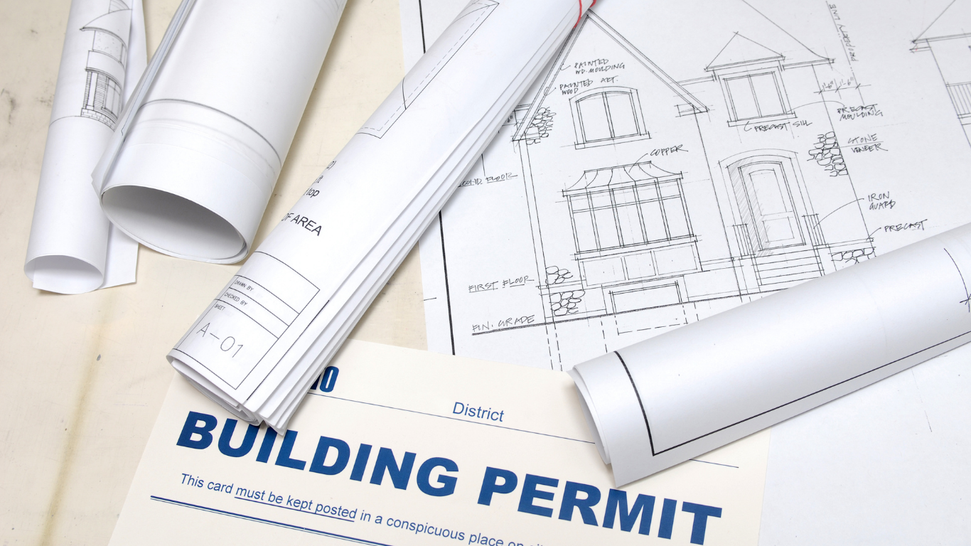 Rolls of blueprints are laying on top of a building permit