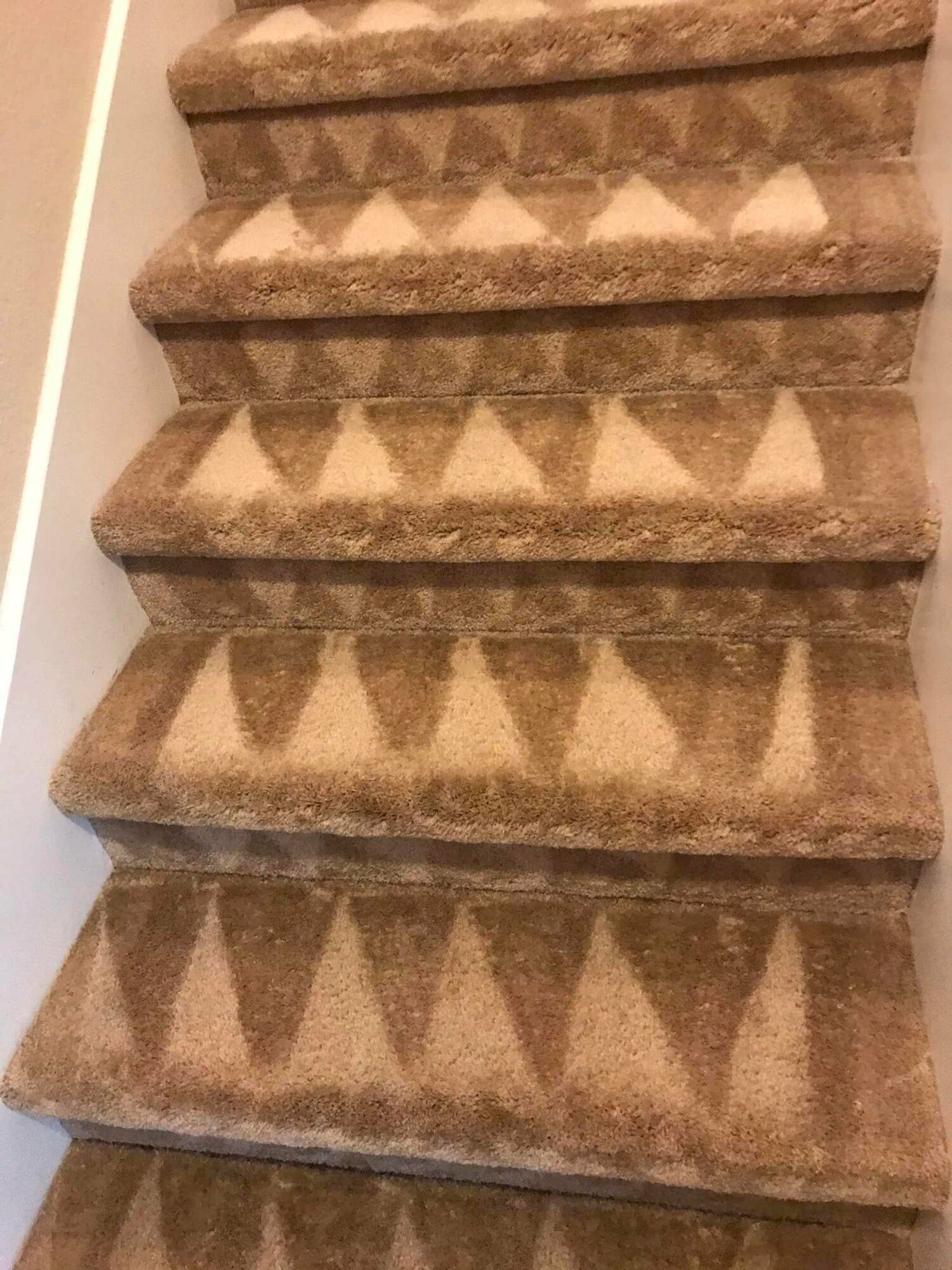 A close up of a set of stairs with a pattern on the carpet.
