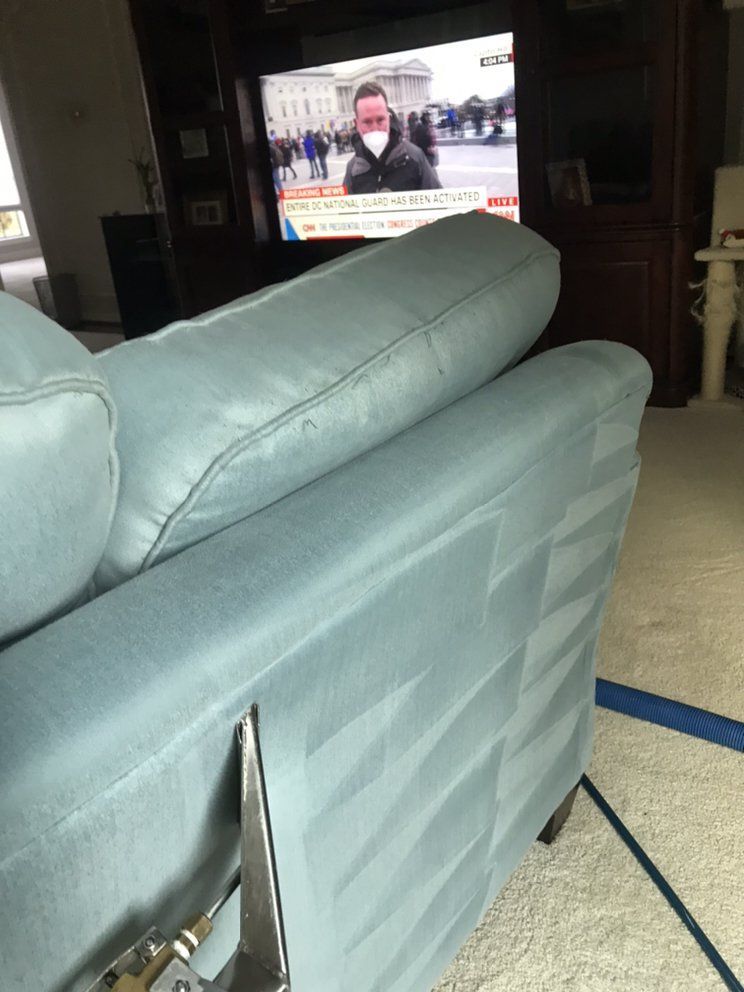 A man wearing a mask is sitting on a couch in front of a television