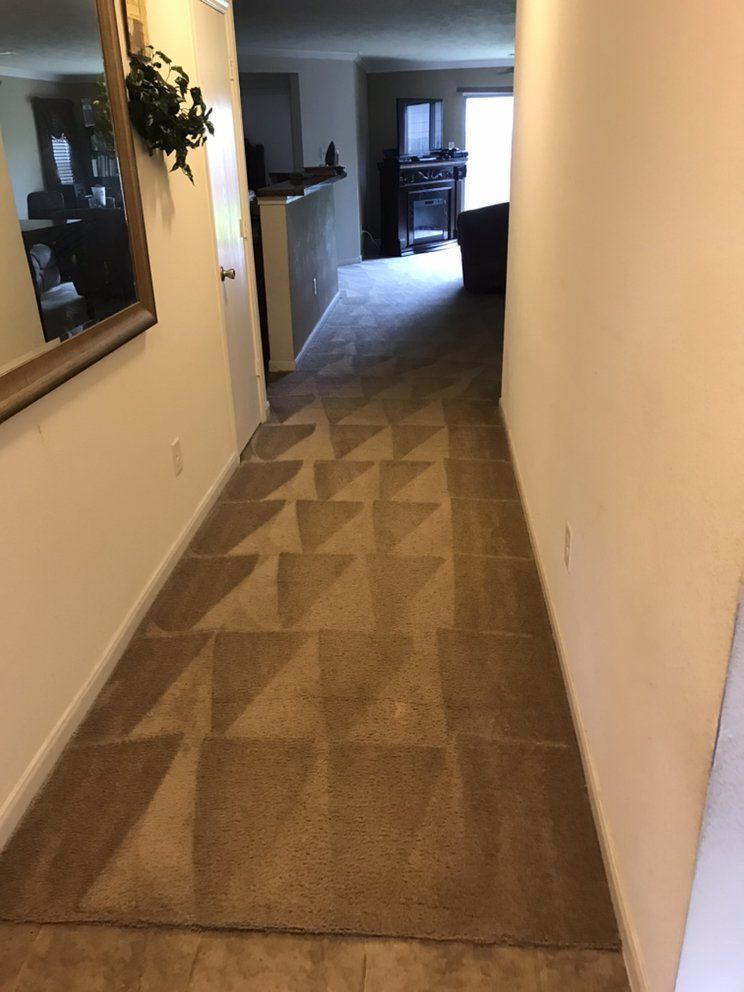 A hallway leading to a living room with a mirror on the wall.