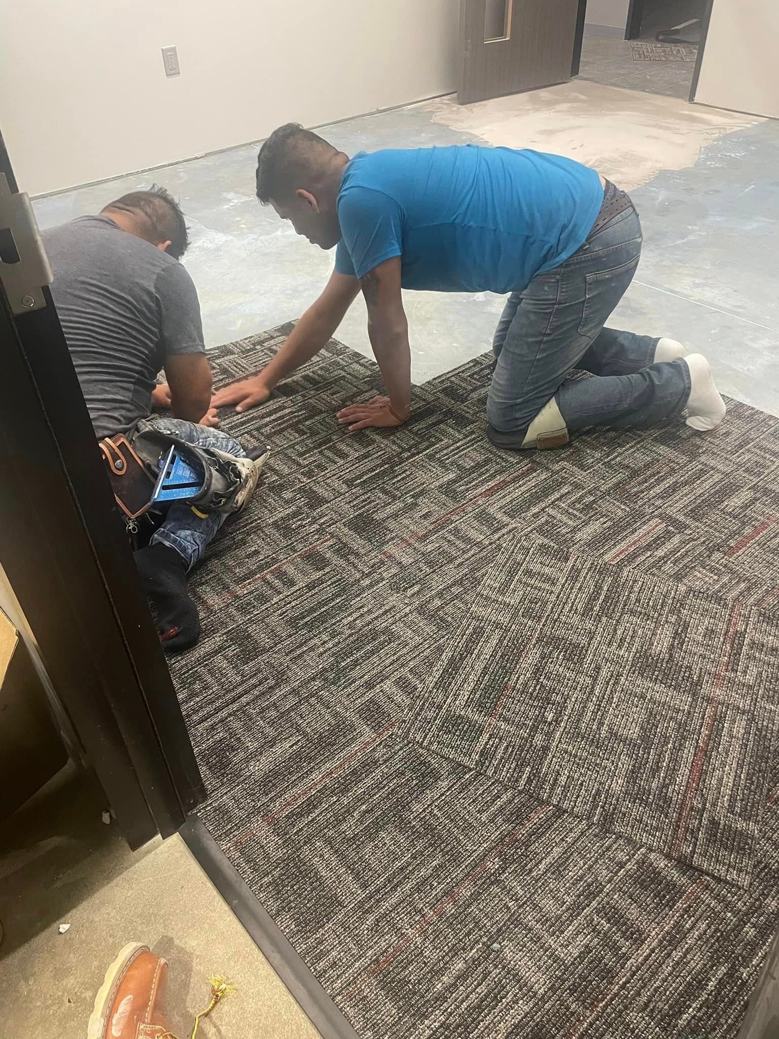 Two men are kneeling on a carpet in a room.