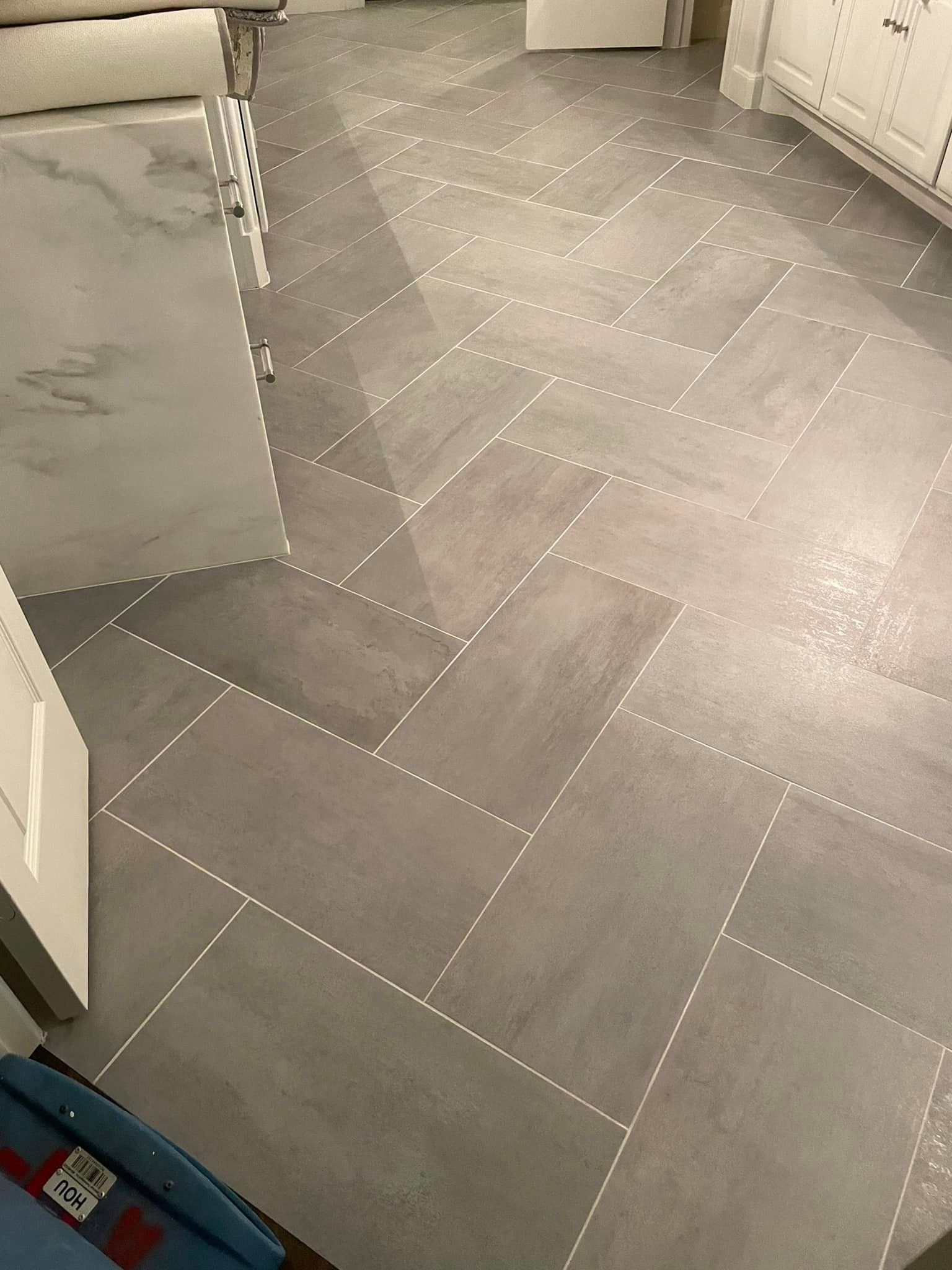 A bathroom floor with a herringbone pattern and a marble counter top.