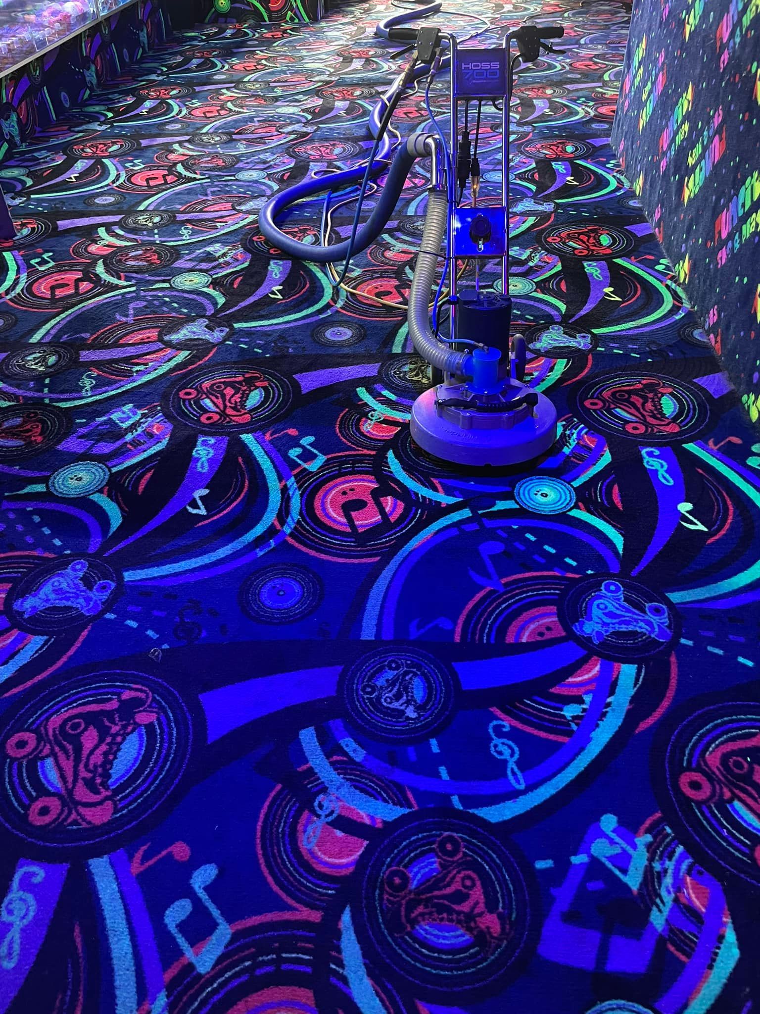 A vacuum cleaner is cleaning a glow in the dark carpet.