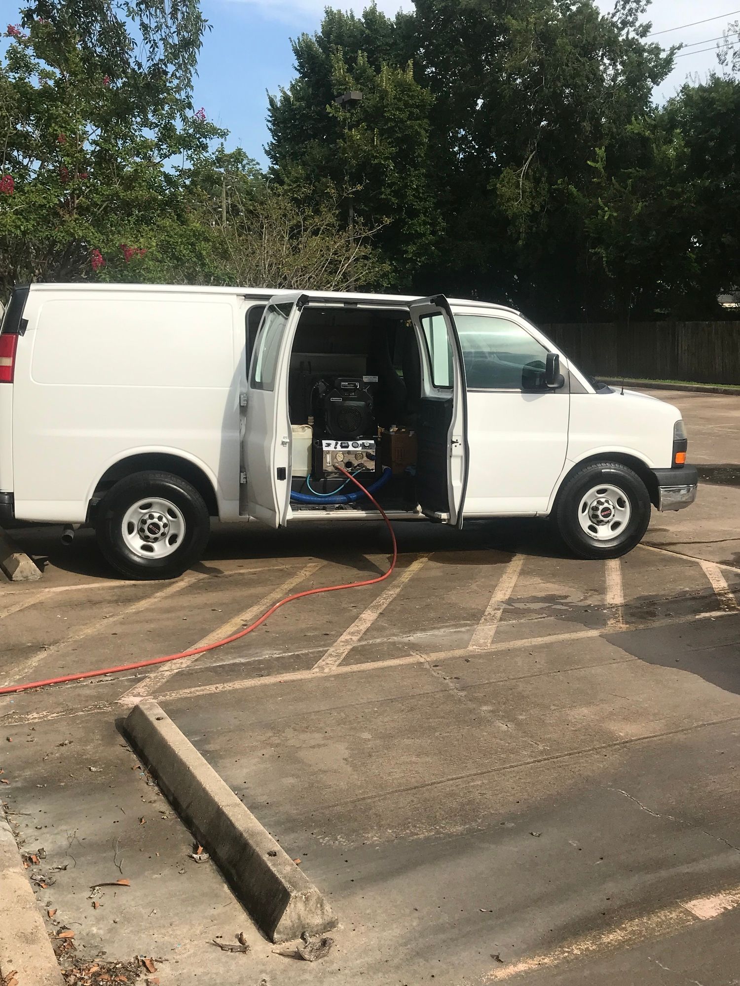 A white van is parked in a parking lot with its doors open.
