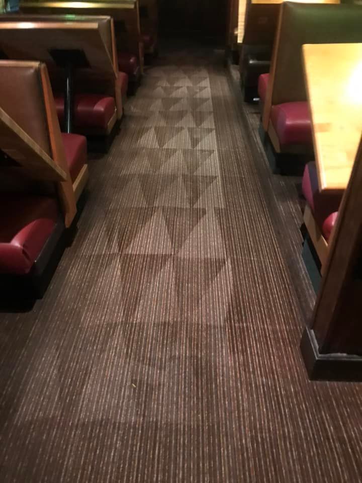 A vacuum cleaner is sitting on a carpet in a bedroom next to a bed.