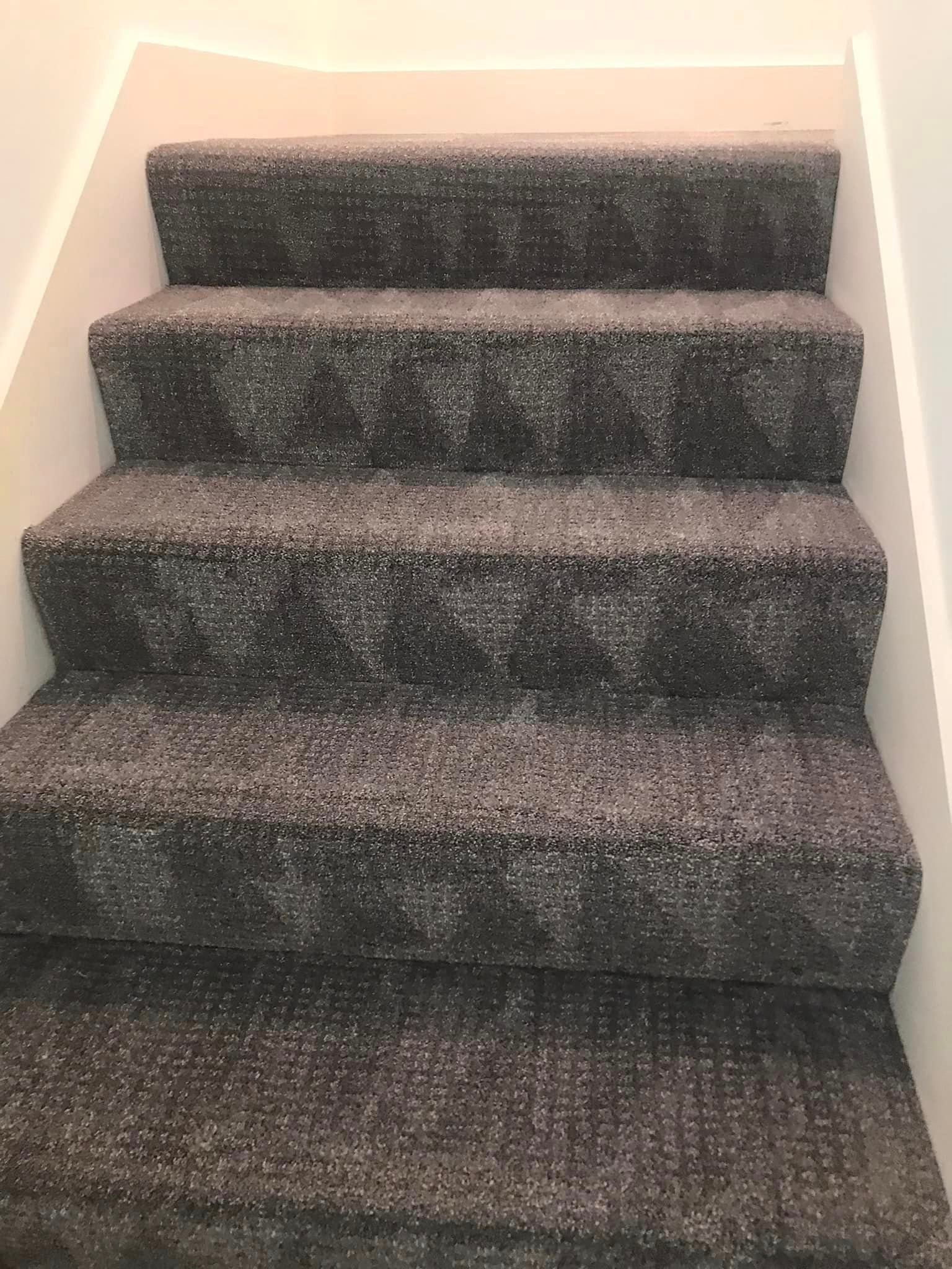 A set of stairs with a gray carpet on them.