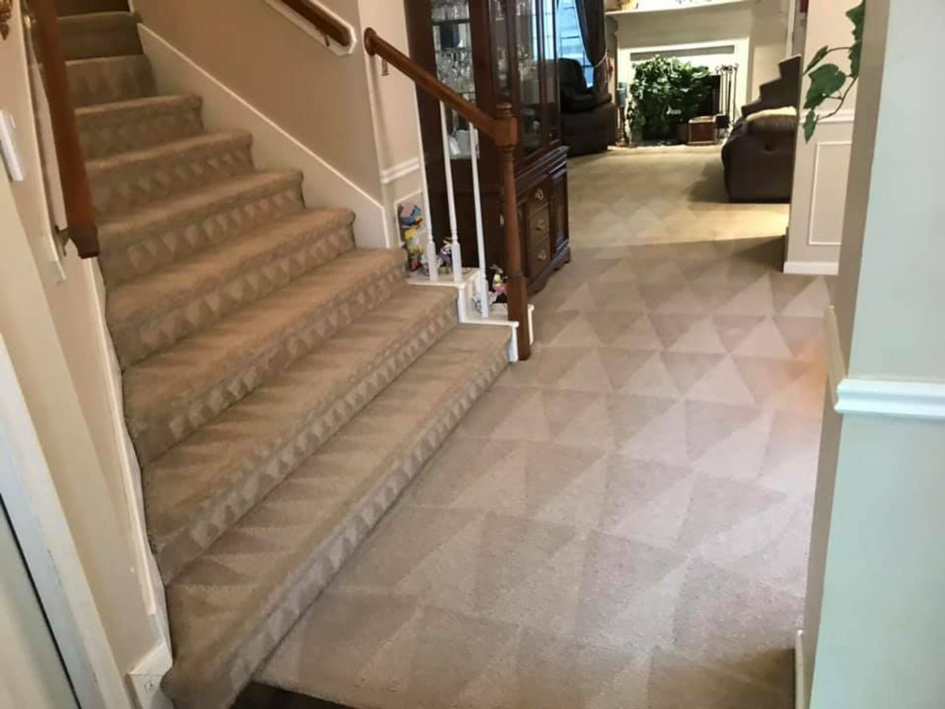 A hallway with stairs leading up to a living room and a fireplace.