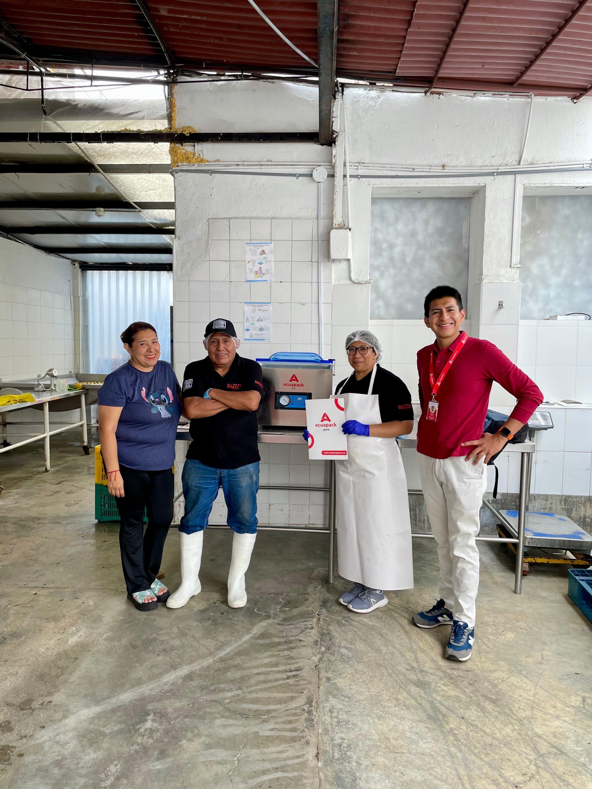 Personas en un stand de una feria comercial revisando materiales. Una mujer con una camisa de lunares habla con dos hombres.