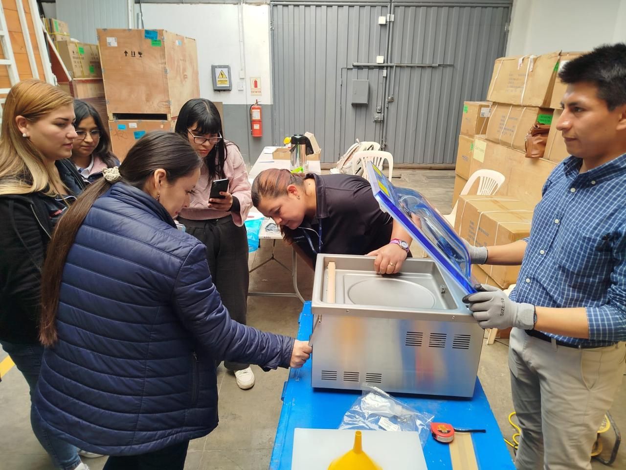 Mujer operando una máquina selladora de cajas en un entorno industrial bien iluminado.