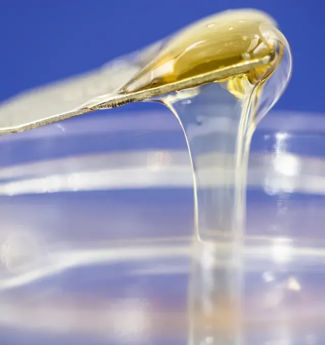 A spoon is pouring liquid into a plastic container