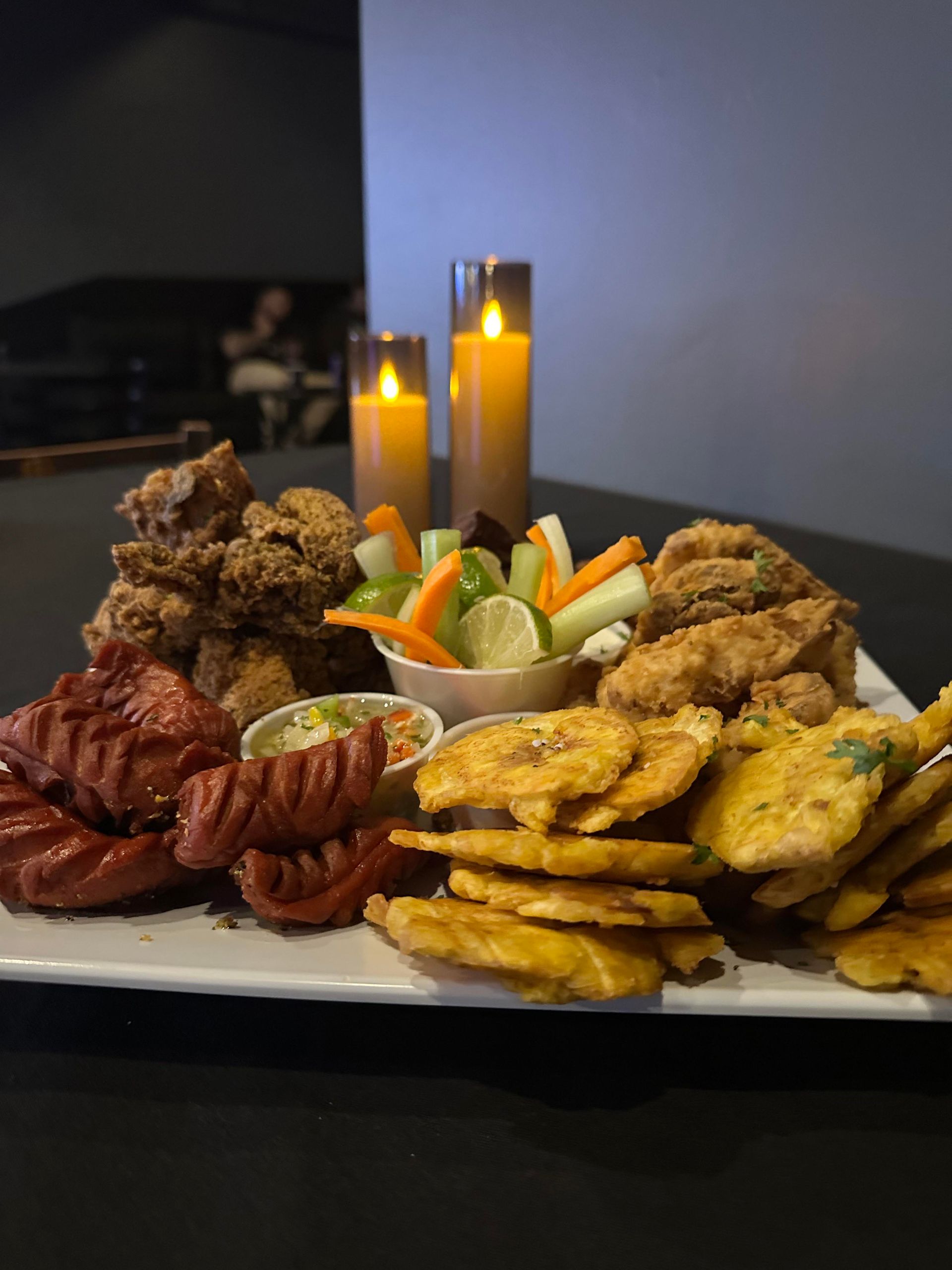 A plate of food with candles in the background on a table.