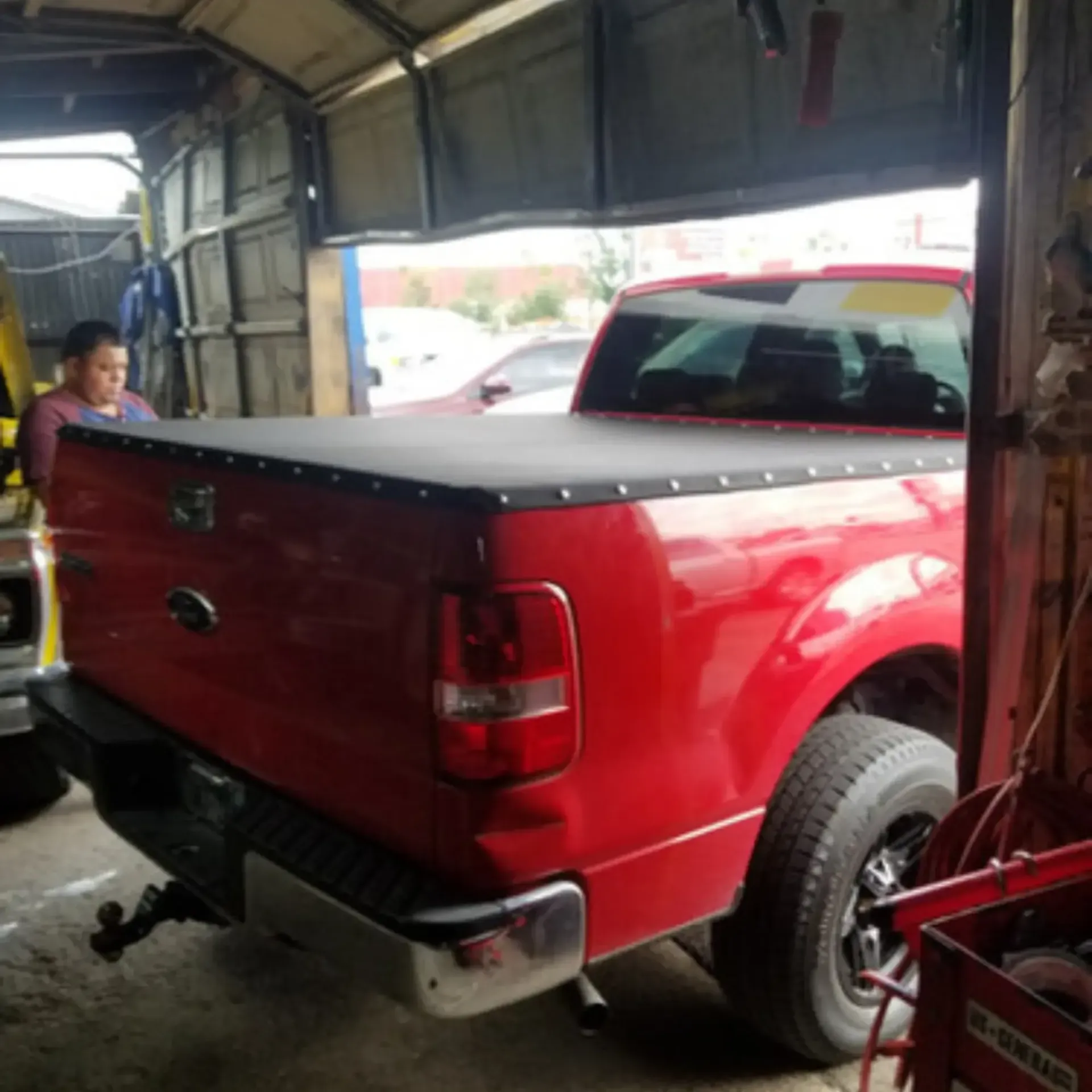 Piece By Piece of Houston LLC
- A red truck with a black tonneau cover is parked in a garage