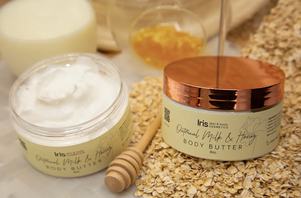 Two men are standing next to each other in the woods looking at a cell phone.