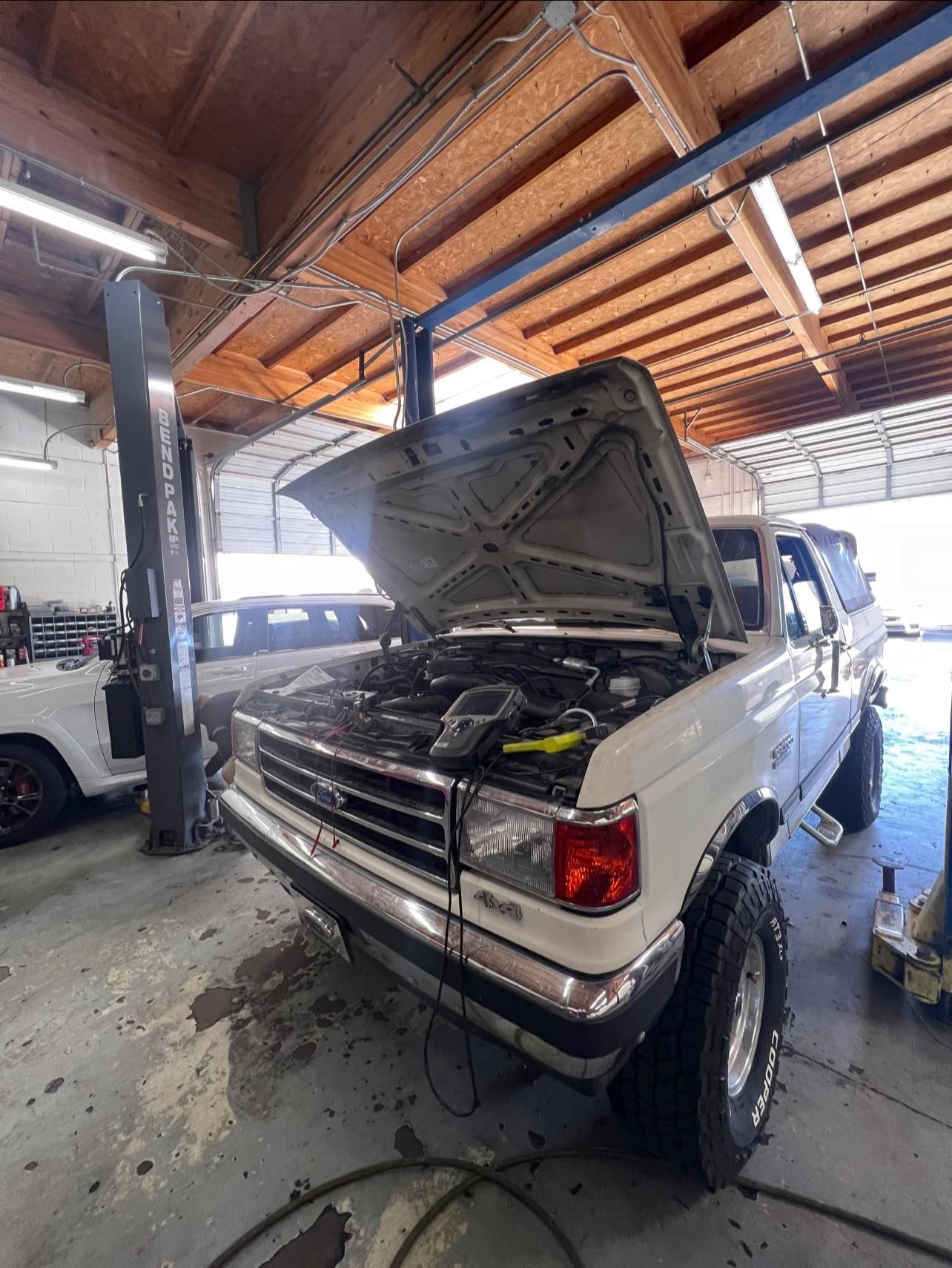 White Ford Bronco with hood up in a repair shop | Greasers Automotive