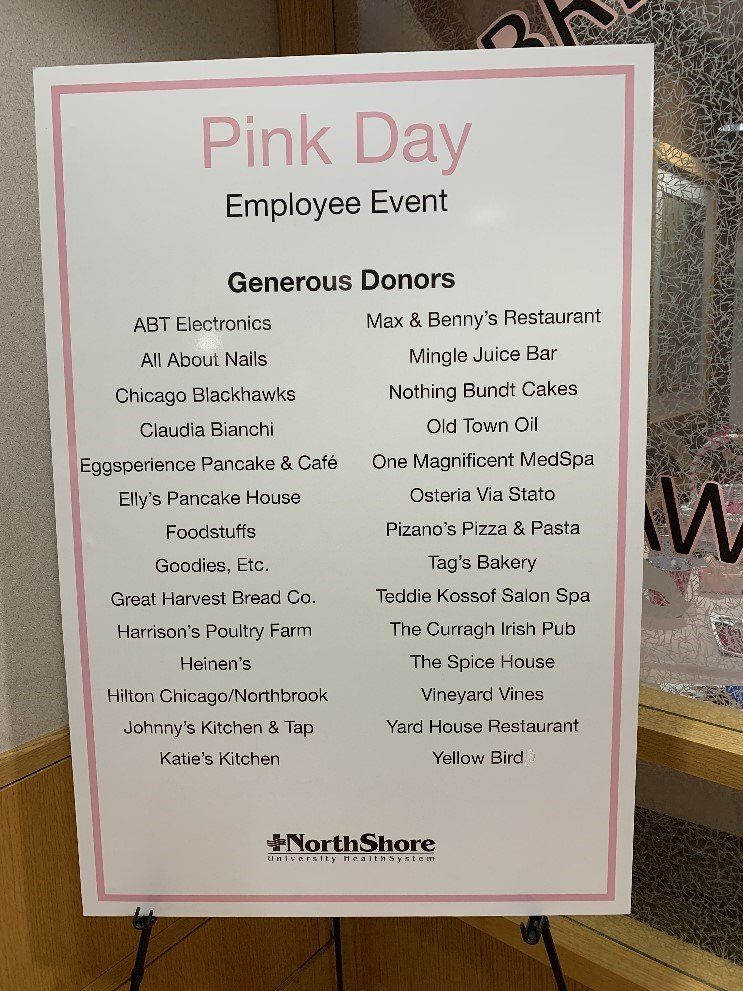 A sign for a pink day employee event is displayed on a easel.