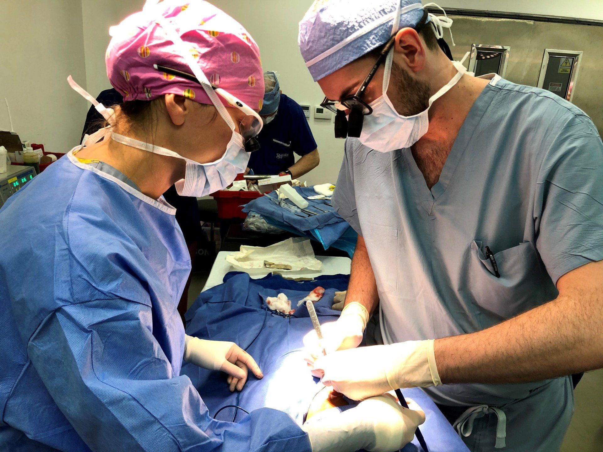 A man and a woman are operating on a patient in an operating room.