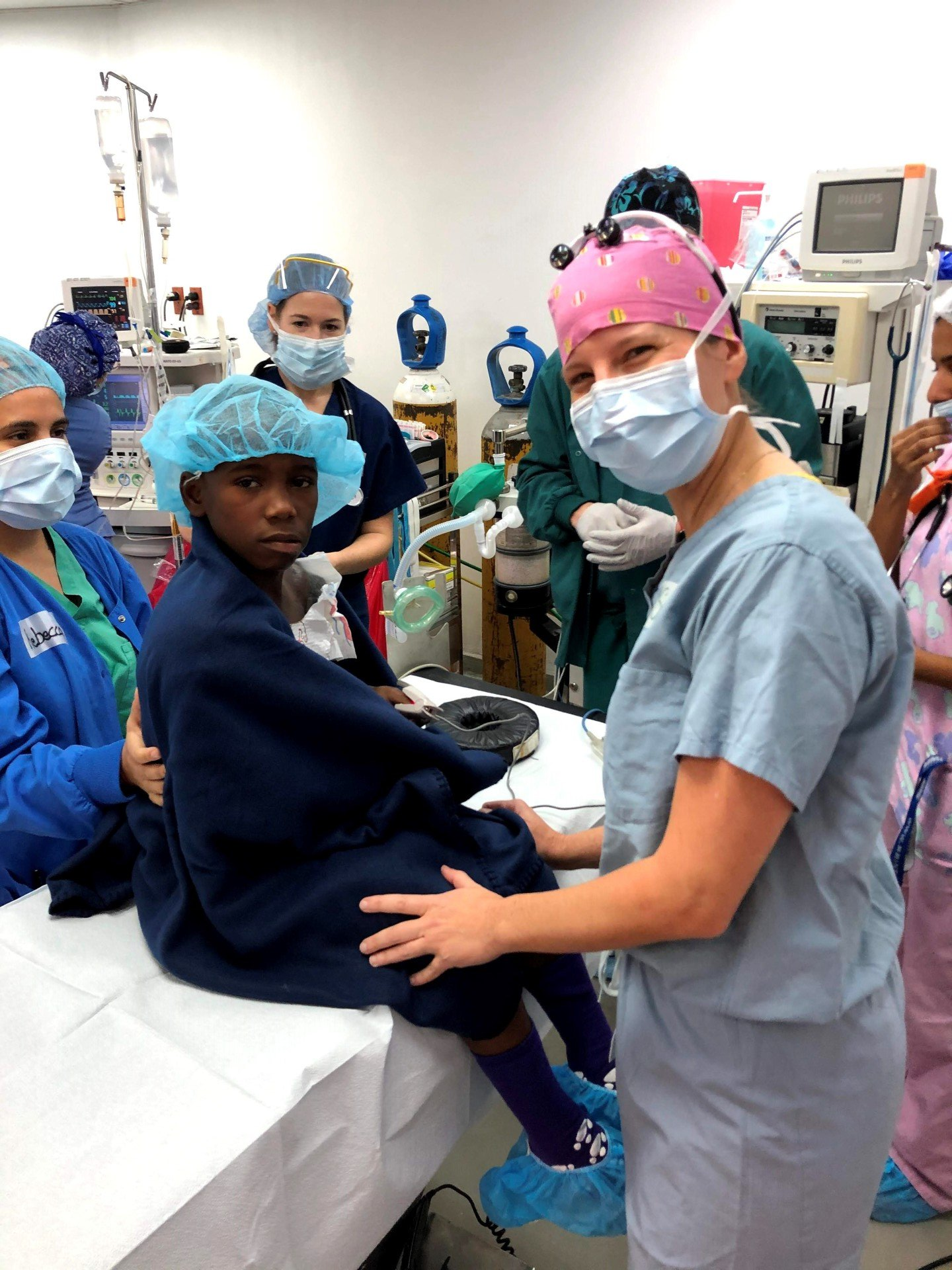 A group of nurses are standing around a patient in an operating room
