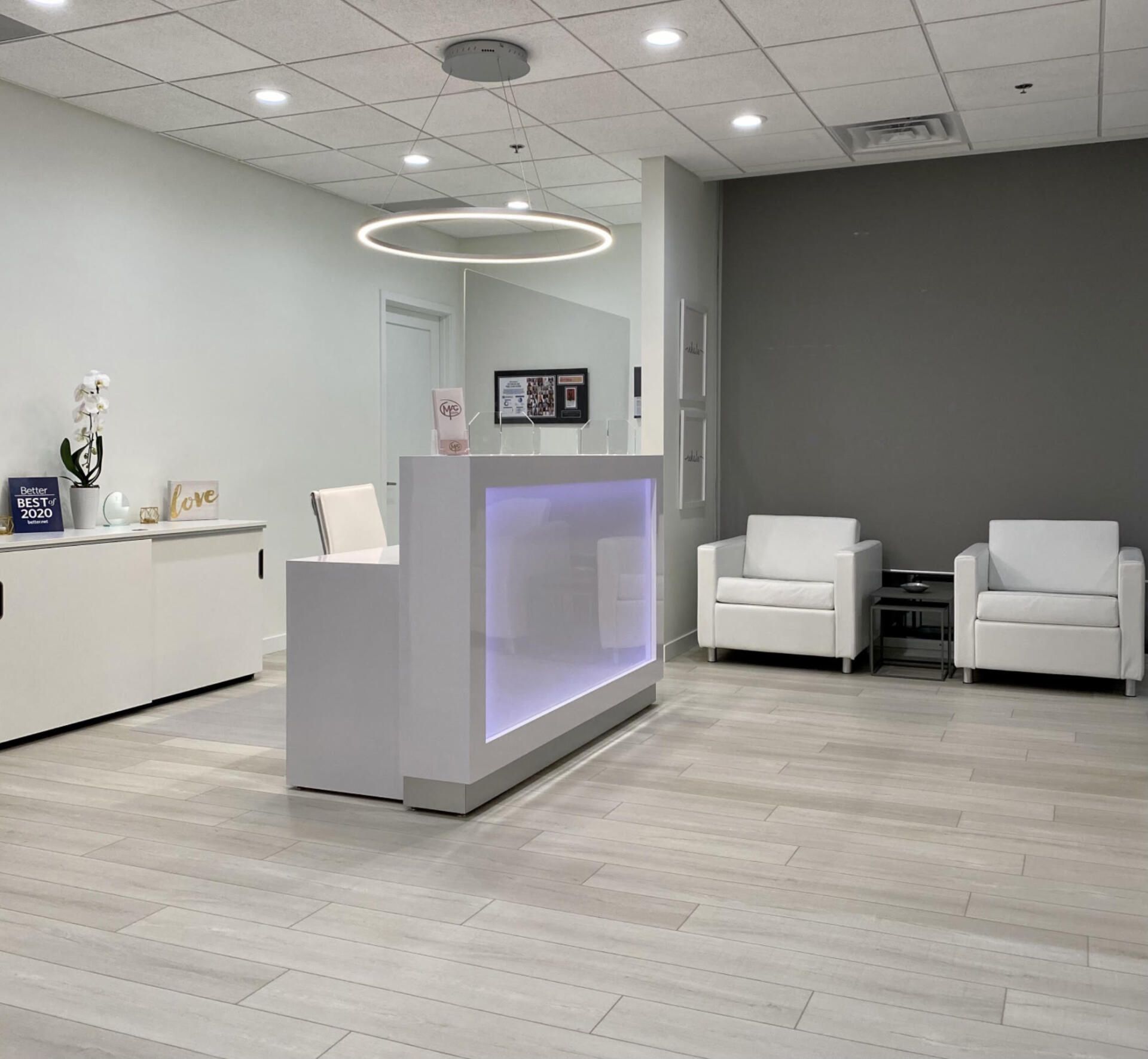 A reception area with a white counter and chairs