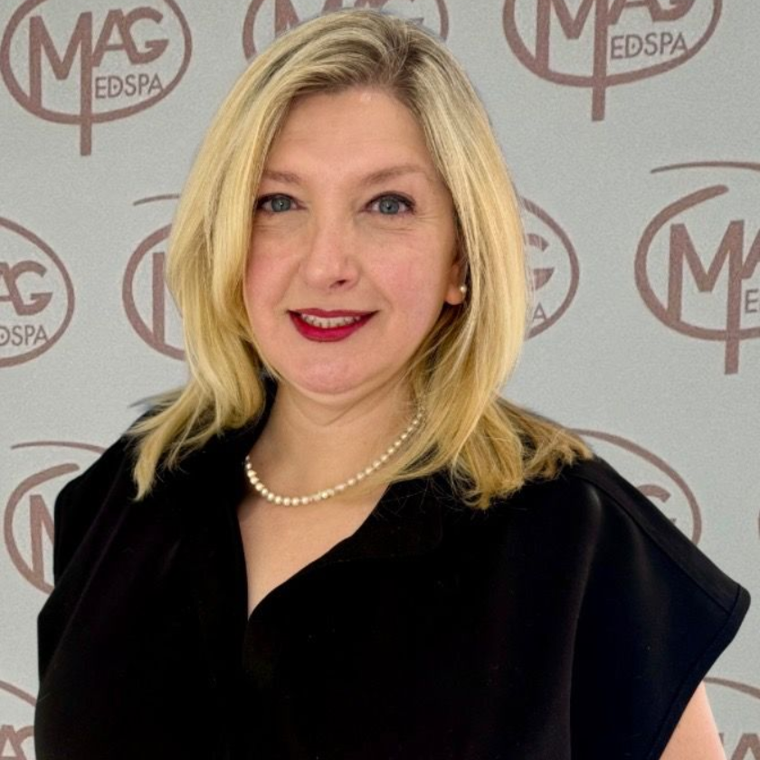 A woman wearing a necklace and hoop earrings smiles for the camera