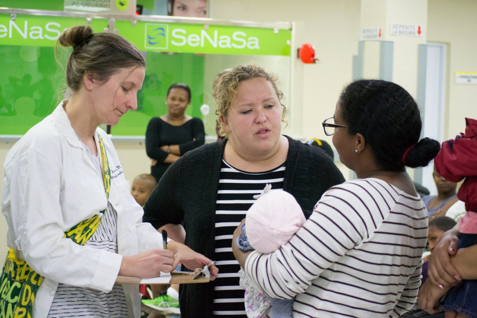 A doctor is talking to a woman holding a baby.