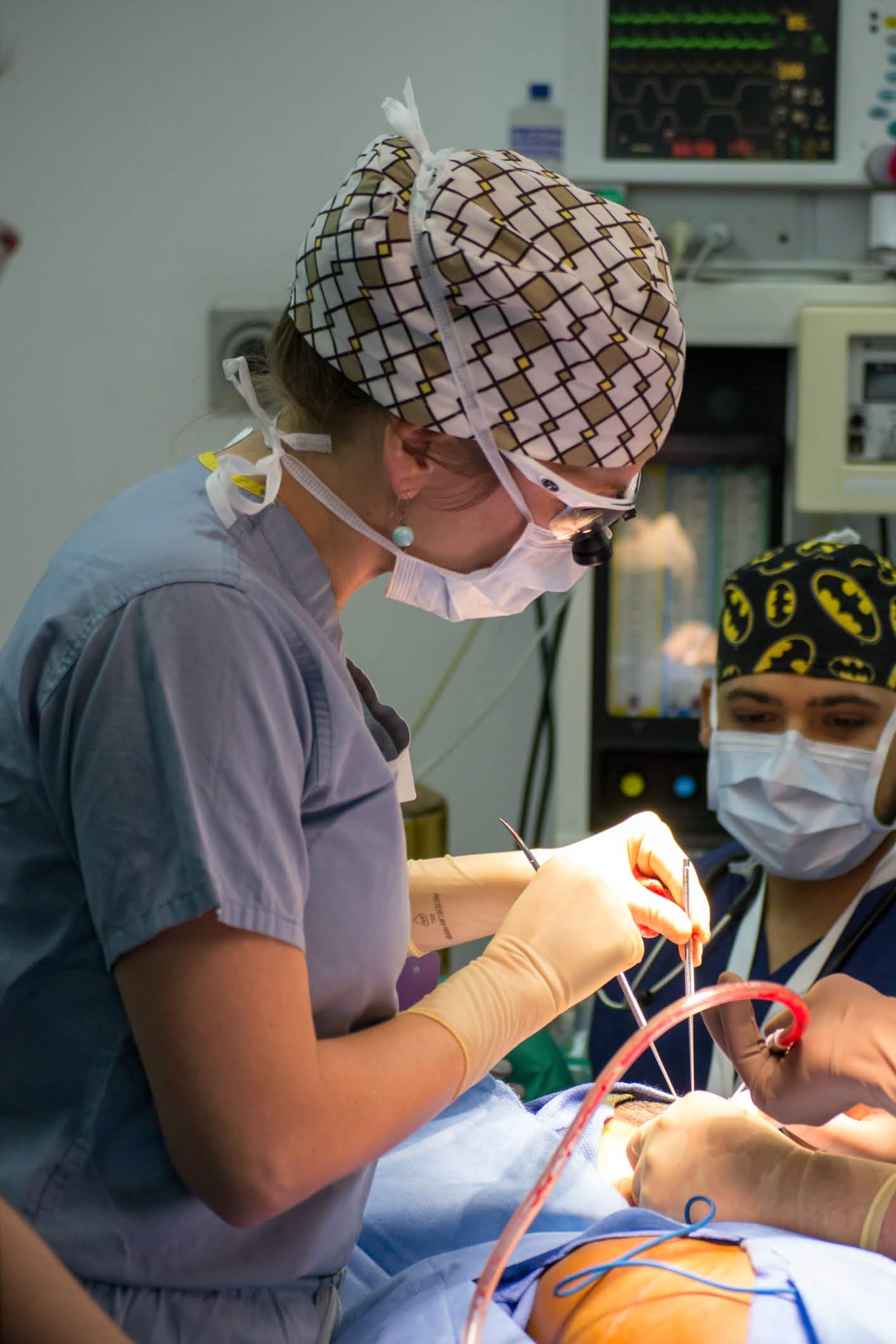 A female surgeon is operating on a patient in an operating room.