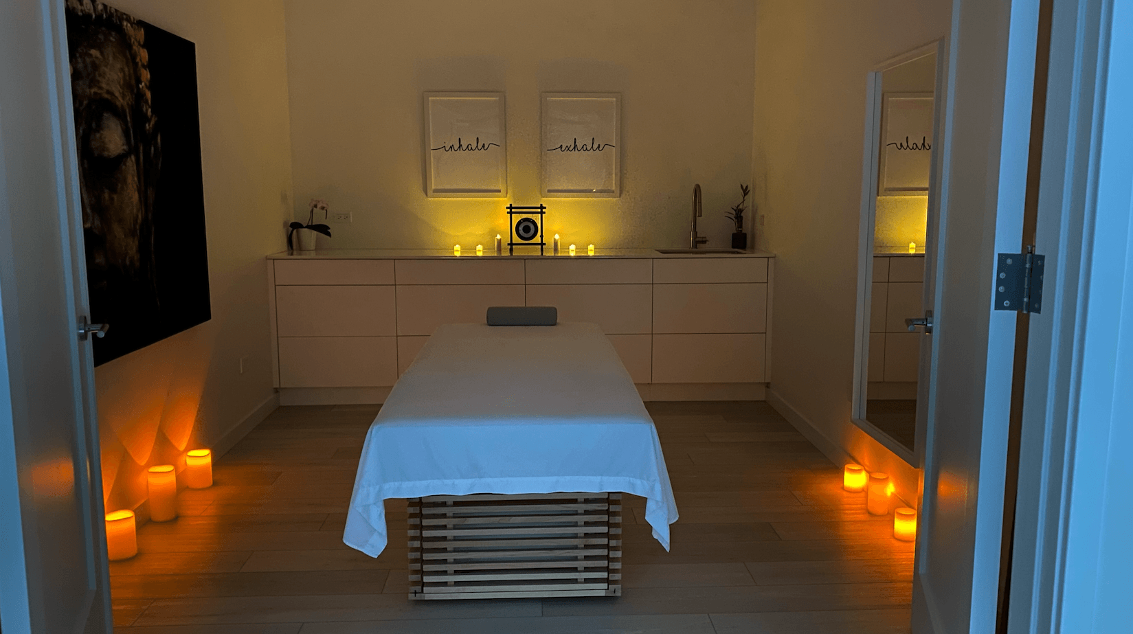 A massage table in a room with candles and a mirror.
