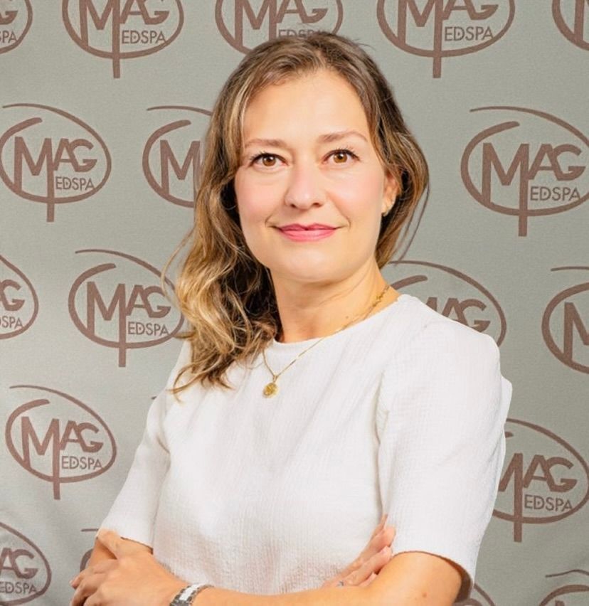 A woman wearing a necklace and hoop earrings smiles for the camera