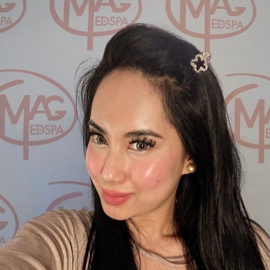 A woman wearing a necklace and hoop earrings smiles for the camera