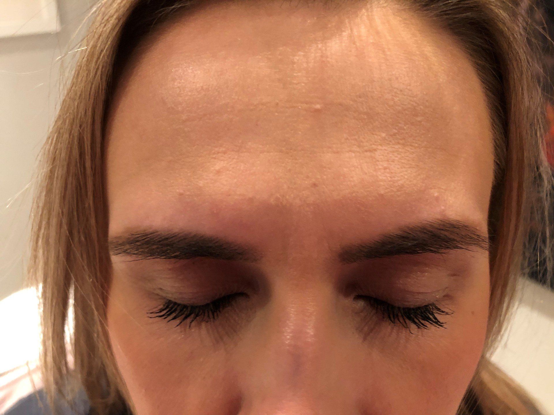 A close up of a woman 's forehead with her eyes closed.