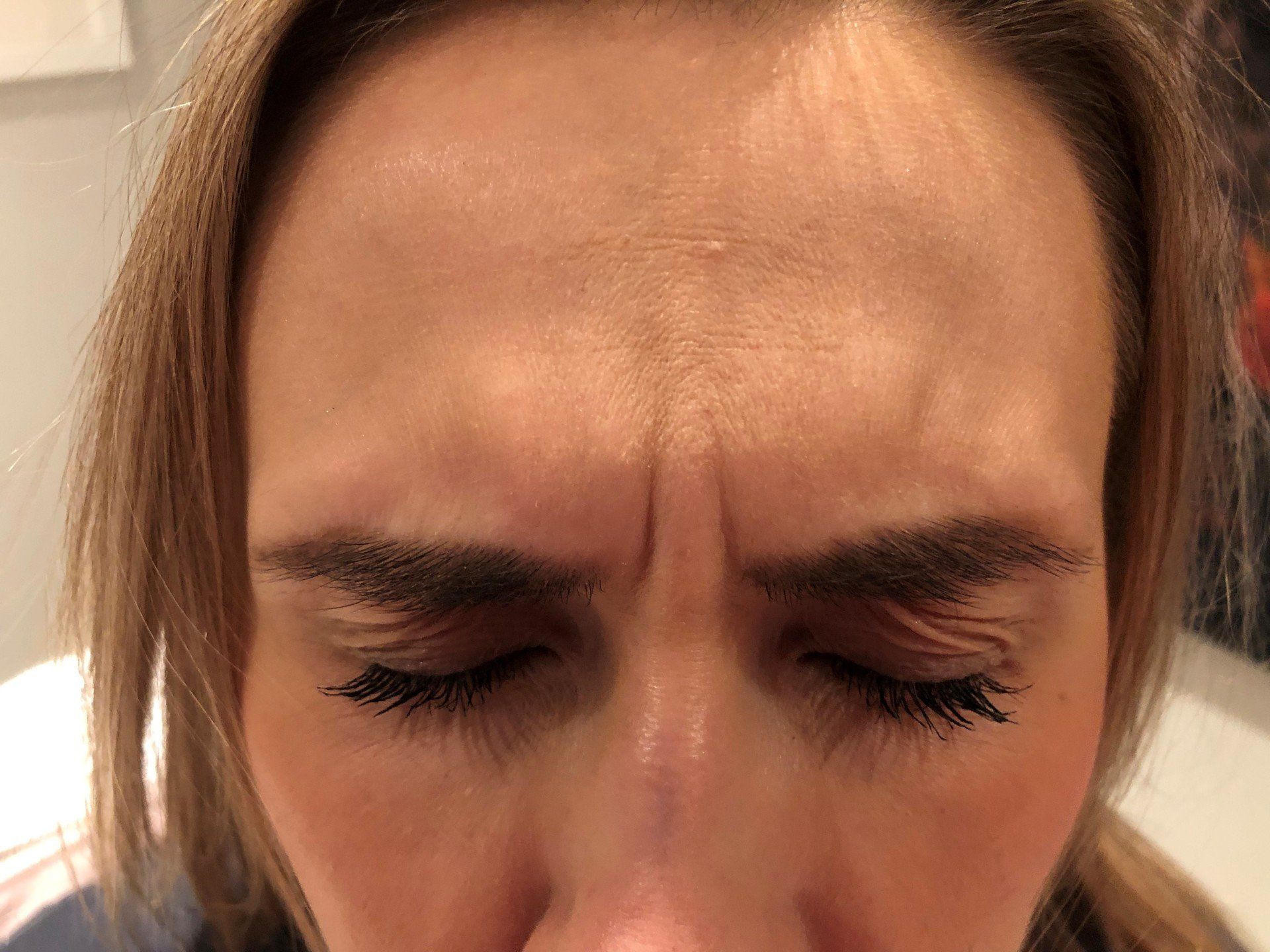 A close up of a woman 's forehead with her eyes closed.