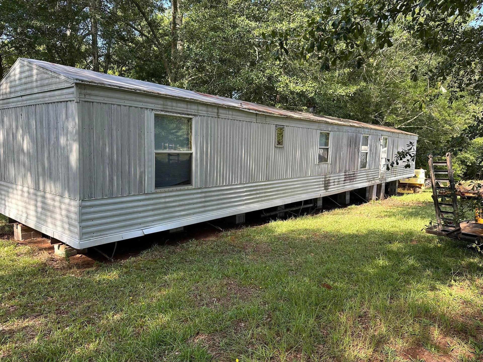A mobile home is sitting in the middle of a grassy field.