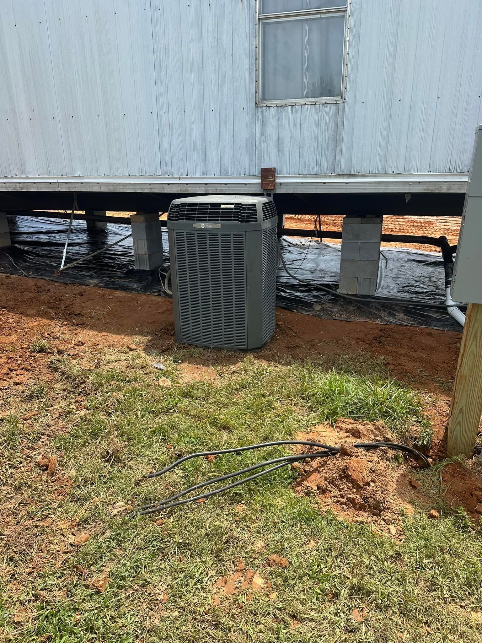 An air conditioner is sitting in the grass in front of a house.