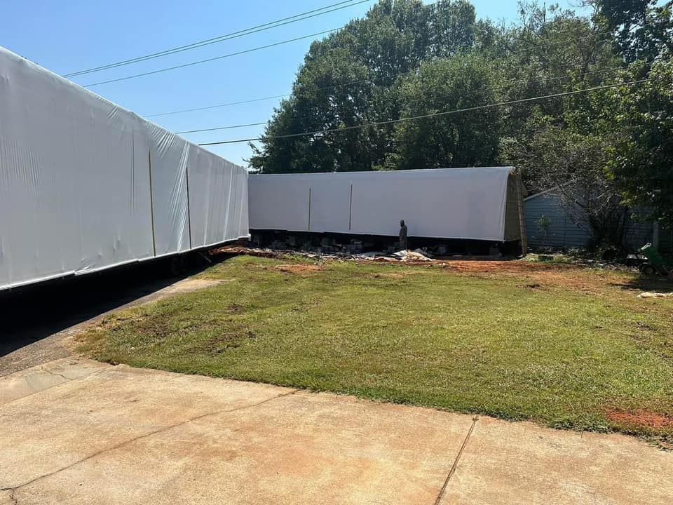 A row of white trailers are parked in a grassy yard.